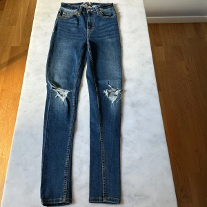 Blå skinny jeans med slitna knän - Snygga blå skinny jeans från 157 med slitna detaljer på båda knäna. 