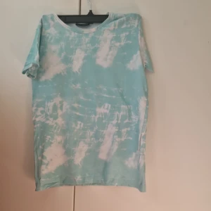 Turkos t-shirt från Reaction - Turkos och vit t-shirt från Reaction med tie-dye mönster. Passar för både tjej och killar. Storlek 146/152
