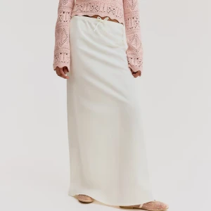 Vit långkjol med snörning i linne - Supersnygg vit långkjol i mjukt linne med enkel snörning i midjan. Kjolen har rak och clean siluett som ger en chill vibe och passar perfekt till sneakers eller sandaler. Lätt och luftig känsla, perfekt för varma dagar.