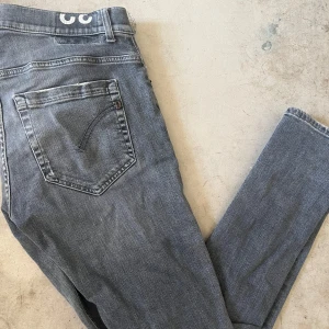 Grå skinny jeans från Dondup, stl 32 - Snygga grå jeans från Dondup i skinny fit-modell. Klassisk femficksdesign med slitningar och tvättade detaljer som ger en cool look. Jeansen är tillverkade i stretchigt denim för skön passform och har normal midja. Perfekta för dig som gillar smalare siluett.