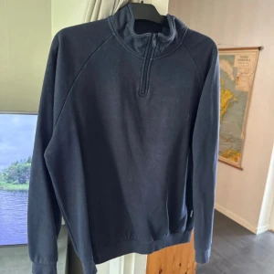 Mörkgrå fleece-tröja från Pier One - Säljer en mörkblå tröja från Pier One med half zip och hög krage. Tröjan har långärmade raglanärmar och är perfekt för kyliga dagar. Enkel och stilren design utan mönster eller extra detaljer, passar dig som gillar basic och bekvämt.