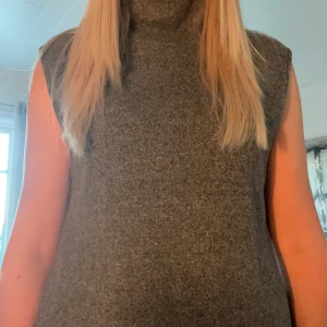 Grå stickad topp med polokrage - Säljer en grå stickad topp med polokrage. Toppen har en rak och loose passform, är ärmlös och har en enkel, stilren look utan synliga detaljer. Perfekt att styla över en långärmad tröja eller skjorta för en chill vibe.