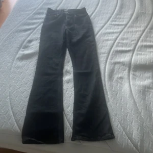 Svarta bootcut jeans från Perfect Jeans - Svarta jeans från Perfect Jeans i storlek 34. Modellen har bootcut-ben, stretch  och klassisk femficksdesign med dragkedja och knapp framtill. Jeansen har en mörk ton och är tillverkade i ett jeansmaterial som känns mjukt och följsamt. Perfekt för dig som gillar en snygg siluett med lite utsvängda ben.