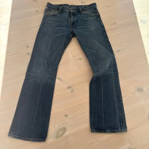 Levi's 507 jeans blå W32 L32 - Säljer ett par klassiska Levi's 507 jeans i mörkblå denim. Modellen har raka ben och fem fickor, med snygga slitningar och detaljerade sömmar. Passar dig som gillar tidlös stil och vill ha ett par jeans med autentisk Levi's-vibe. Pris kan diskuteras😁🙌