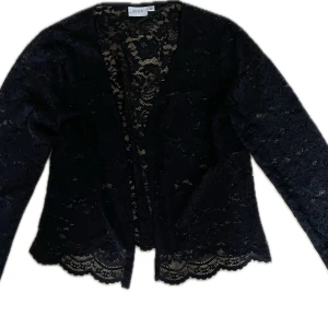Svart spetsjacka från Vila, stl 40 - Svart cardigan jacka från Vila i storlek 40, helt i spets med långa ärmar. Snygga detaljer med vågig spetskant nedtill och genombrutet mönster över hela jackan. ❤️❤️