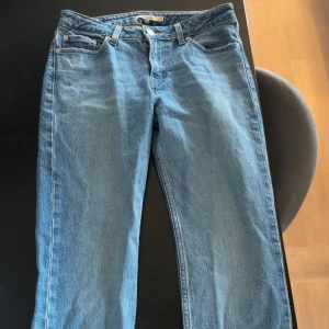 Levi's jeans ljusblå low pitch straight - Klassiska Levi's jeans i ljusblå tvätt med rak passform och fem fickor. Jeansen har normal midja, knappgylf och den ikoniska läderpatchen bak. Perfekta för dig som gillar tidlös stil och vill ha ett par jeans som funkar till allt.