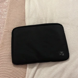 Svart datorväska  - Minimalistisk svart datorväska, perfekt för att skydda din laptop. Väskan har en stilren rektangulär form, mjuk insida och dragkedja längs kanten. Märkt med 'Computer Case No.11' på framsidan. Enkel och clean design som funkar till plugget eller jobbet.