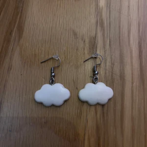 Molnformade vita örhängen - Supergulliga örhängen formade som små moln i vit färg. Hängande modell med metallkrokar och plaststopp. Perfekt för dig som vill ha en lekfull och unik detalj till din stil. Passar både till chill och när du vill sticka ut lite extra.