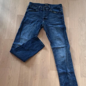 Blå slim jeans från Jack & Jones - Snygga blå jeans från Jack & Jones, modell Slim/Glenn. jeansen är i storleken 31/32. Jeansen har en slim passform, klassisk femficksdesign och är tillverkade i mjukt denimtyg. Perfekta för dig som gillar en smalare siluett och stilren look.