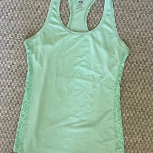 Mintgrön linnetopp från H&M - Snygg mintgrön linnetopp från H&M med racerback och leopardmönstrade paneler på sidorna. Perfekt för träning eller chill dagar. Tunt och mjukt material som andas bra.