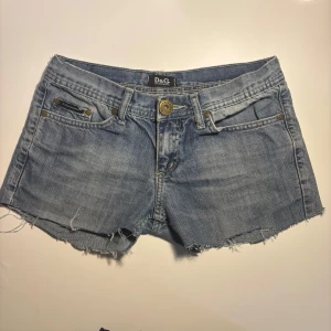 Vintage D&G Dolce & Gabbana shorts - Skit coola vintage shorts från D&G. Trendig Y2K-stil med stor D&G-logga i brunt imitationsläder på baksidan. Bra vintage skick inget tydligt slitage   Storlek: W28 (motsvarar ca S / 36) Modell: Low waist   Pris går att diskutera.  Hör gärna av dig om du har fler frågor!