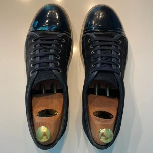Lanvin Cap Toe - Snygga svarta/mörkblå lanvins med glans och en klassisk vit sula. Skorna är i bra skick men lite slitna på insidan i hälen men går lätt att fixa. Skulle säga att skicket lätt är 8/10 och inga större defekter. Skriv vid minsta fundering och pris kan diskuteras!