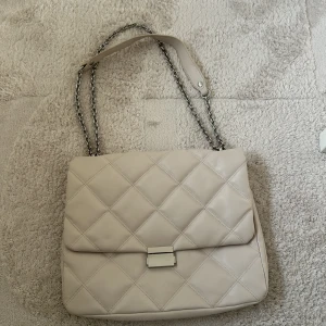 Beige quiltad axelväska med kedja - Snygg beige väska som man får plats me jätte mycket saker, kommer aldrig till användning 💕