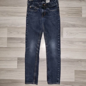 Blå jeans med dragkedjor bak - Snygga blå jeans med klassisk femficksdesign och coola dragkedjor på bakfickorna. Jeansen har smal passform, normal midja och är gjorda i mjukt denimtyg. Perfekta för dig som gillar detaljer och vill ha en stilren men ändå unik look.