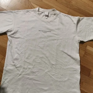 Vit t-shirt med text från H&M - Vit t-shirt från H&M med svart texttryck på både bröstet och ryggen. På ryggen står det 'ONE DAY EVEN THIS WILL BE HISTORY' upprepat och citatet är signerat Yrsa Daley-Ward. Passar som Oversize ,  rund halsringning i mjuk bomull. Finns en extremt liten fläck på ryggen som jag tror kan tvättas bort, hör av er vid eventuella frågor💕