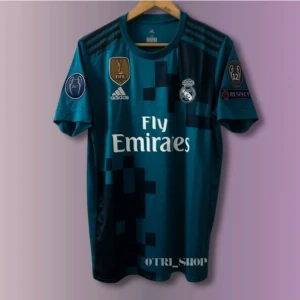Real Madrid Ronaldo 7 bortatröja Adidas - Snygg Real Madrid bortatröja från Adidas med Ronaldo 7 på ryggen. Tröjan är marinblå med digitalt pixelmönster, korta ärmar och broderade klubbmärken samt Fly Emirates-tryck på bröstet. Perfekt för dig som älskar fotboll och Cristiano Ronaldo.