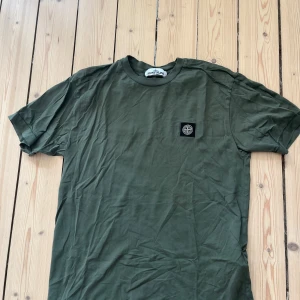Grön t-shirt från Stone Island - Snygg grön t-shirt från Stone Island med klassisk logopatch på bröstet. T-shirten har rund halsringning och korta ärmar. Tillverkad i mjuk bomull som känns skön mot huden. Skick 9/10, storlek M