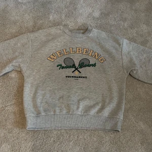 Grå sweatshirt med tennis-tryck - Grå sweatshirt från Gina tricot i storlek XS/34. Tröjan har rund hals, ribbade muddar och en loose passform.