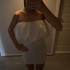 Vit axelbandslös klänning - Säljer denna vita volang klänning ifrån Zara. Aldrig använd och i fint skick❤️