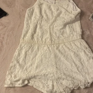 Vit spetsjumpsuit från UNIQ YOUNG - Superfin vit jumpsuit från UNIQ YOUNG i storlek 146/152. Jumpsuithar ett vackert spetslager över hela och är ärmlös med smala axelband. Perfekt för sommarens alla tillfällen när du vill känna dig extra söt och fräsch.