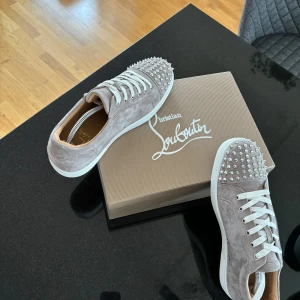 Grå mocka sneakers Christian Louboutin - Unik färg som man inte ser ofta av Louboutin. Storlek 45 jag brukar har 45 i skor och dessa passade perfekt. Tillkommer: box, extra nitar och extra snöre. Skriv om du har frågor😀