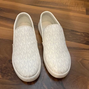 Vita slip-on sneakers från Michael Kors - Vita slip-on sneakers från Michael Kors, använda fåtal gånger. Storlek 34. 