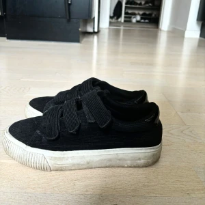 Svarta sneakers med korsband - Säljer mina super fina svart vita sneakers då de ej kommer till användning längre, bra skick och endast synlig slitage på insidan av skon som man kan se på bild 2 samt även lite på den vita sulan💕