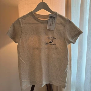 Brandy Melville  - Snygg ljusbeige t-shirt ifrån Brandy Melville med tryck 'Nantucket Island Massachusetts' och segelbåt både fram och bak. Storlek Onesize, ordinare pris 231kr