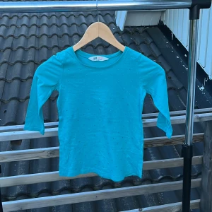 Turkos topp med små prickar H&M - Turkos långärmad topp från H&M i mjuk bomull. Toppen har små diskreta prickar över hela framsidan och en klassisk rund halsringning. Perfekt för dig som gillar färg och enkel stil.