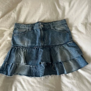 Jeanskjol med volanger från Gina Tricot - Supersnygg jeanskjol från Gina Tricot med volanger och råa kanter. Kjolen är blå, har klassiska jeansfickor och bälteshällor. bara använd 2 gånger eftersom att jag gillar mer low waist  än vad den var , köpte för stor storlek tyvärr 💙