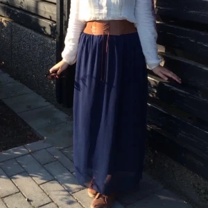 Pirate corset kjol - Blå långkjol med bred midja i brunt med en snörningsdetalj framtill för att ge korsett pirate vibe. Ett hörn i kanten är trasig.