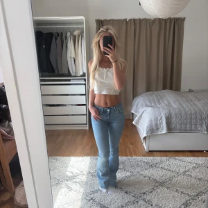 Ljusblå bootcut jeans från lager 157  - Säljer ett par ljusblå jeans med bootcut passform och klassisk femficksdesign. Jeansen har låg midja och är tillverkade i mjukt denimtyg som sitter snyggt över höfterna och låren. Perfekta för dig som gillar en retro vibe och vill ha ett par jeans som sticker ut. Str xxs 