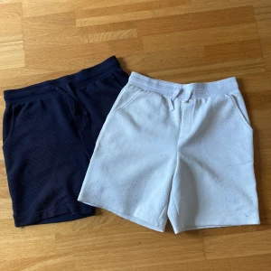 2-pack shorts från Primark, blå & vita - Två par sköna shorts från Primark, ett par i mörkblått och ett par i vitt. Båda har elastisk midja med snörning och sidfickor. De vita har diskret fiskbensmönster, medan de blå är enfärgade. Perfekta för sommaren och chill dagar. Kommer sälja båda tsm för 150kr