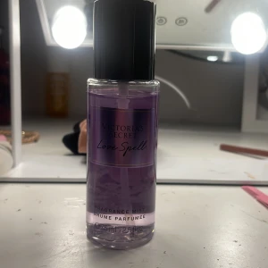Victoria's Secret Love Spell mist - En snygg och feminin body mist från Victoria's Secret i doften Love Spell. Flaskan är genomskinlig med lila vätska och svart lock. Rymmer 75 ml och har en stilren, modern design som passar perfekt på sminkbordet. Helt ny och endast sprayad några gånger!!