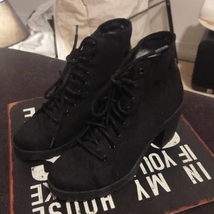 Svarta boots med klack och snörning. Nya.  - Snygga svarta boots med grov sula och klack. Skorna har snörning framtill och är tillverkade i ett tygmaterial som ger en cool look. Rund tå och robust design gör dem perfekta för höst och vinter. Passar dig som gillar en edgy stil. Endast testade i fem min så är alltså som nya. 