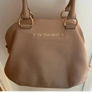 Beige handväska från Victoria's Secret - Säljer min Victoria’s Secret väska!! den är så snygg och jag tycker om färgen otroligt mycket, den är rosa/beige!!! och är perfekt storlek! 💘💘