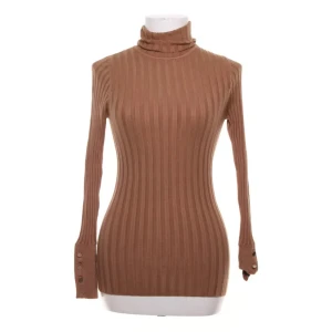 Ribbad polotröja från Gina Tricot XS - Snygg ribbad polotröja i beige/kamel från Gina Tricot Equestrian Collection. Tröjan är tight i modellen, har knappar vid ärmslut och hög polokrage. Perfekt att styla med jeans eller kjol för en trendig lyxig look.