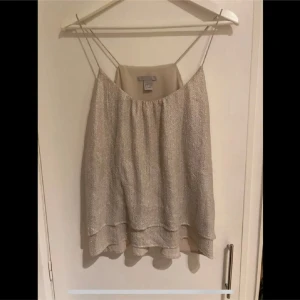 Glittrig linnetopp  - Säljer en superfin beige glittrig topp från H&M i storlek 36. Använd vid ett tillfälle, inga fel på den 