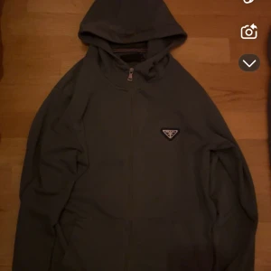 Prada sett - Snygga mörkgrå mjukisbyxor från Prada med dragsko i midjan och klassisk logga på benet. Byxorna har en relaxed fit och är perfekta för chill dagar. Tillverkade i mjukt material för maximal komfort.