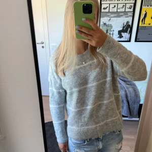 Grå randig stickad tröja i mohair - Mysig stickad tröja i ljusgrå med vita ränder! Tröjan är bland annat tillverkad av mohair och ull vilket gör att den håller värmen bra. Perfekt på sommarkvällar eller till hösten!🩶🤍🩶🤍