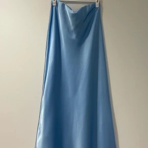 Ljusblå långkjol i satin - En lång satin kjol i färgen sky blue, använd endast en gång.