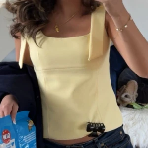 Gul linnetopp med breda axelband - Snygg ljusgul linnetopp med breda axelband och fyrkantig ringning. Toppen är croppad och har en stilren, enkel design som passar perfekt till jeans eller kjol. Perfekt för varma dagar och ger en fräsch look. storlek S men har sytt in banden så den sitter som Xs och använd 1 gång PRIS går att diskutera vid snabb affär (kom med pris förslag)