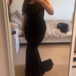 Svart glittrig långklänning - Supersnygg svart långklänning med glittrigt tyg och figurnära passform. Klänningen är axelbandslös och har en elegant släp. Perfekt för bal eller fest. Använd 2 gånger är nästan som ny.