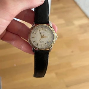 Tissot damklocka med svart läderband - Vintage damklocka köpt på Göteborgs auktionsverk. Mycket fint skick och fungerar precis som den ska.
