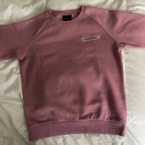 Rosa Peak Performance sweatshirt - En stilren rosa sweatshirt från Peak Performance med broderad logga på bröstet. Tröjan har rund hals, långa ärmar och ribbade muddar vid ärmslut och nederkant. Perfekt för en chill och avslappnad look.
