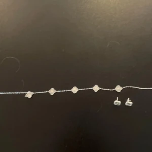 Sött silverset med blommor - Set med halsband och örhängen i silverfärg, båda med små blommor i fyrklöverform. Kedjan är tunn och smyckena har en glansig finish. Perfekt för dig som gillar stilrena och söta detaljer. Använt endast en gång och säljer örhängen för 200 och halsbandet för 250 men båda två för 400 