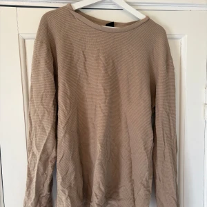 Beige långärmad tröja från FSBN - Säljer en beige långärmad tröja från FSBN i slim fit-modell. Tröjan har en enkel och stilren design med rund halsringning och är tillverkad i ett mjukt material. Perfekt för en avslappnad och snygg look. 