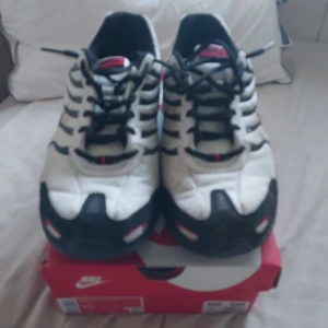 Nike Air Max sneakers i vitt och svart med röda detaljer - Nike Air Max sneakers med vit mesh, svarta och röda detaljer samt svart sula. Klassisk Nike-logga på sidan och hälen. Skorna har snörning och en sportig design med synlig Air Max-dämpning. Använda 2-3 gånger pris kan diskuteras 