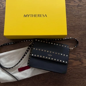 Svart axelväska med nitar från Valentino - Valentino väska som inte kommer till användning längre. Köpt från MyTheresa 2020 men har mest legat orörd de senaste 4 åren, så skicket är nästan helt oanvänt. Original kvitto finns. Nypris ca 15.000. Levereras med dustbag och originalkartong.