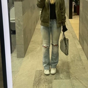 Ljusblå Nelly jeans  - Säljer ett par ljusblå jeans med raka ben och slitna hål på båda knäna. Jeansen har normal passform och klassisk femficksdesign. Perfekta för en avslappnad och trendig look.